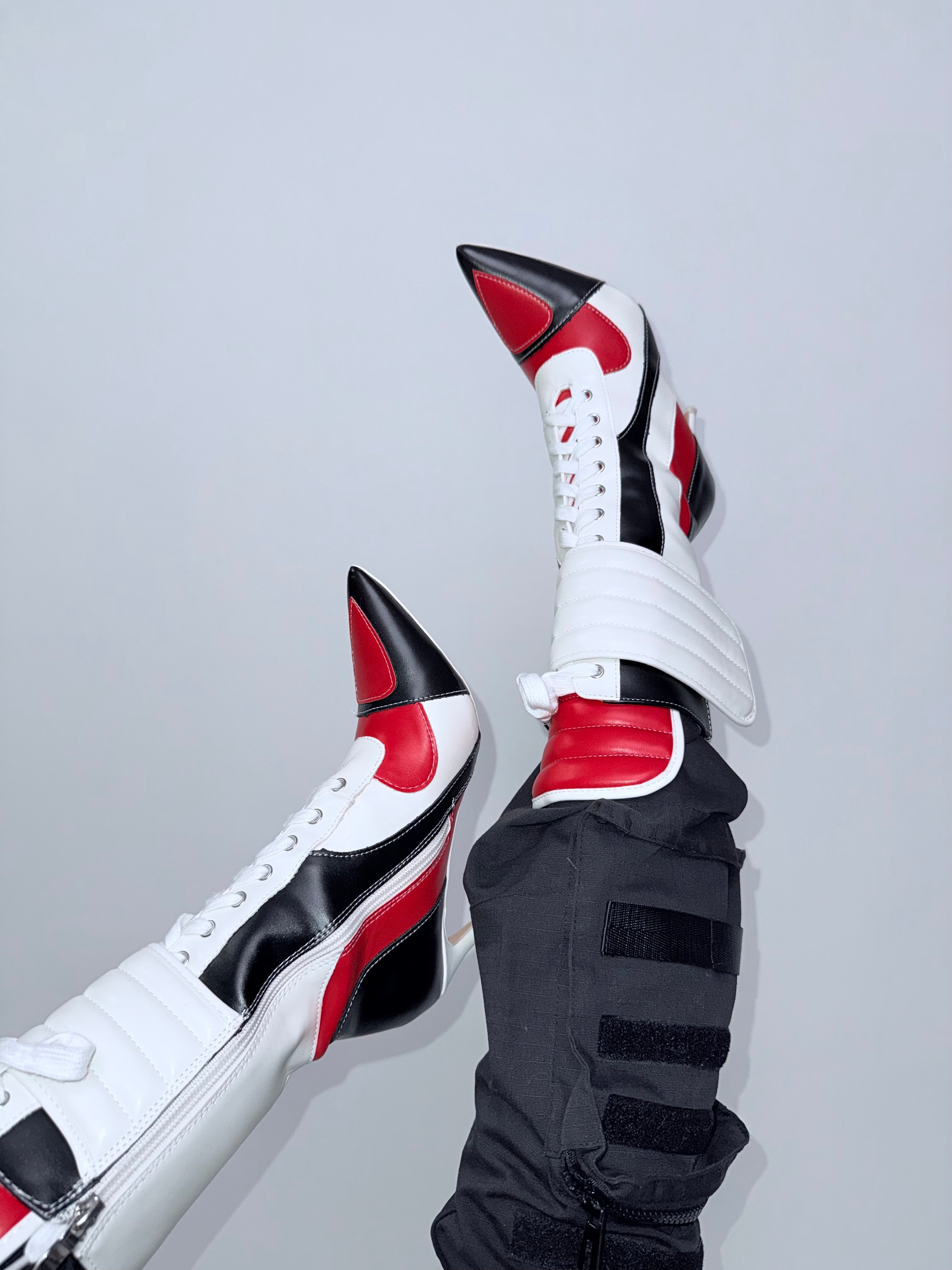 White, black, and red high-top sneakers on a light gray background