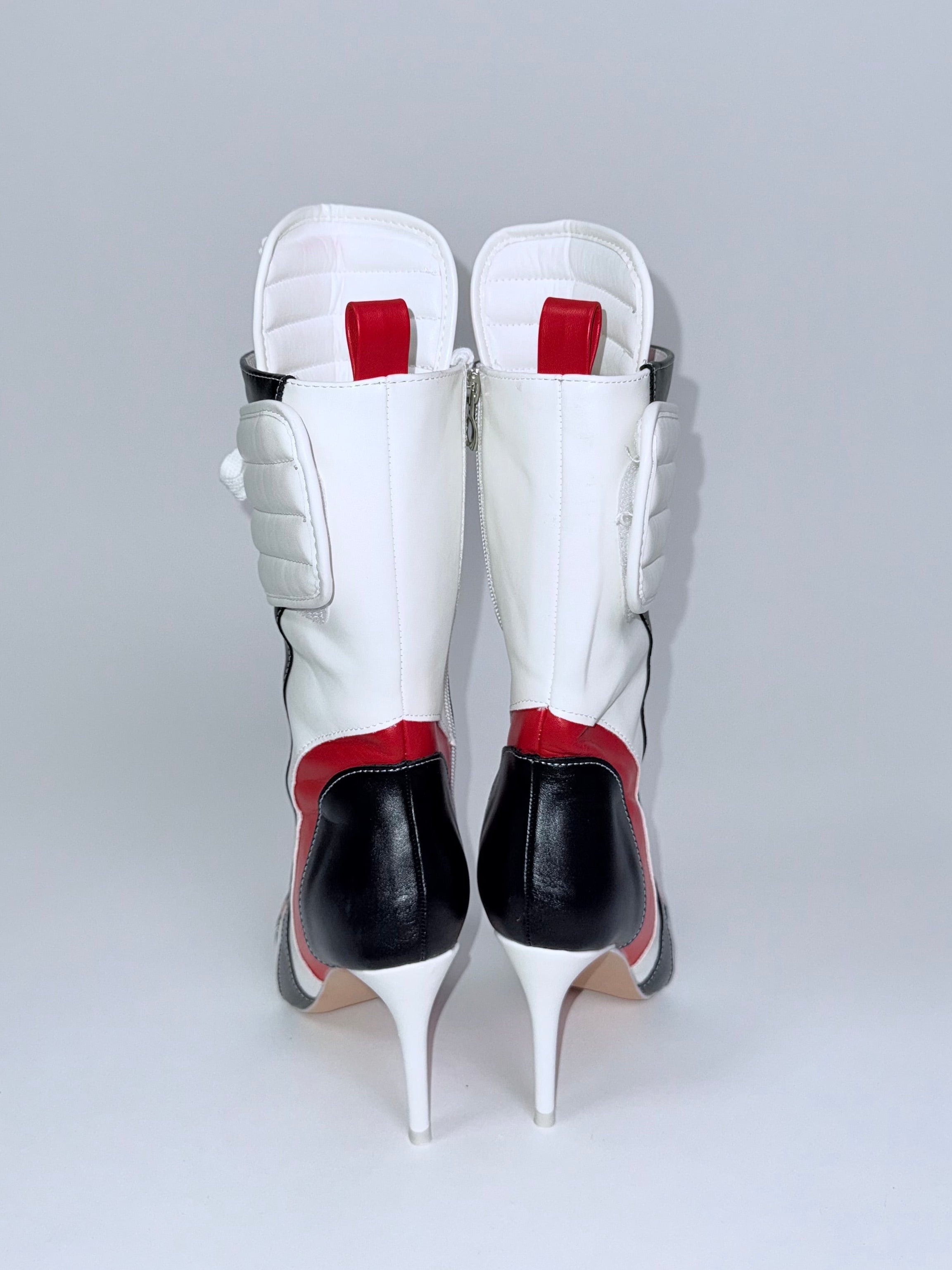 White high-heeled shoes with red accents on a light gray background