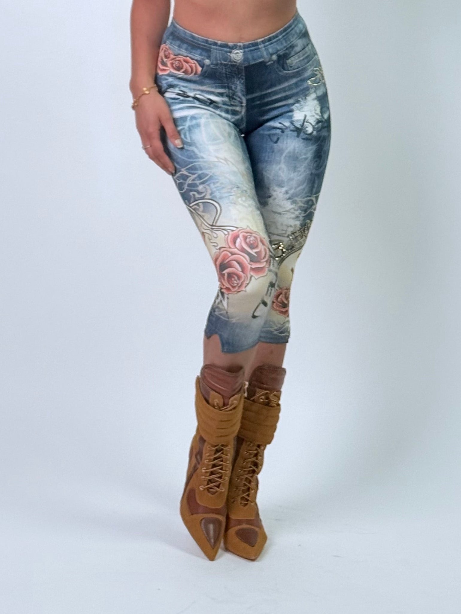 Person wearing a patterned top, jeans  and camel boots with a white background