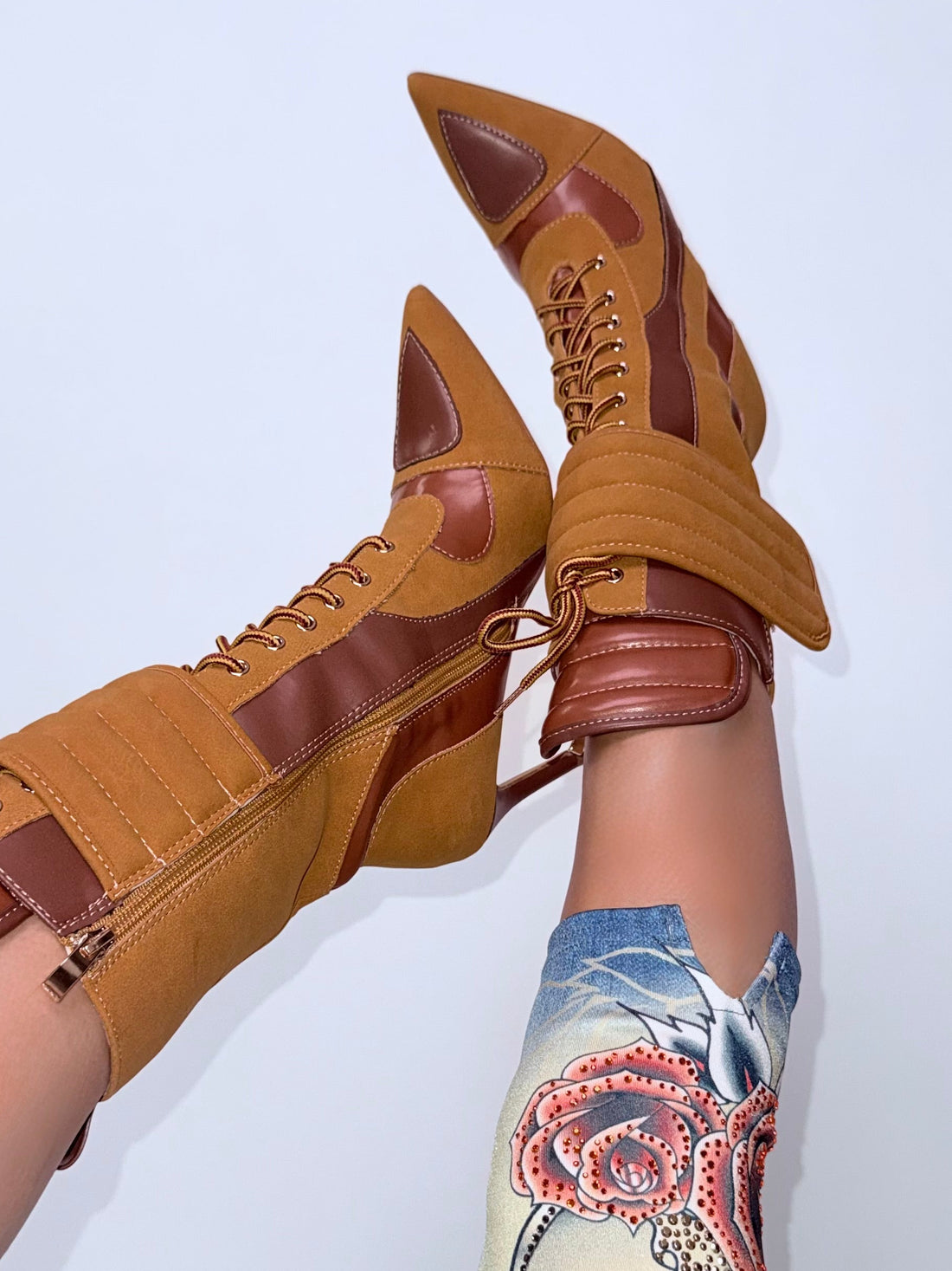 Tan high-heeled shoes with brown straps worn by a person on a light gray background