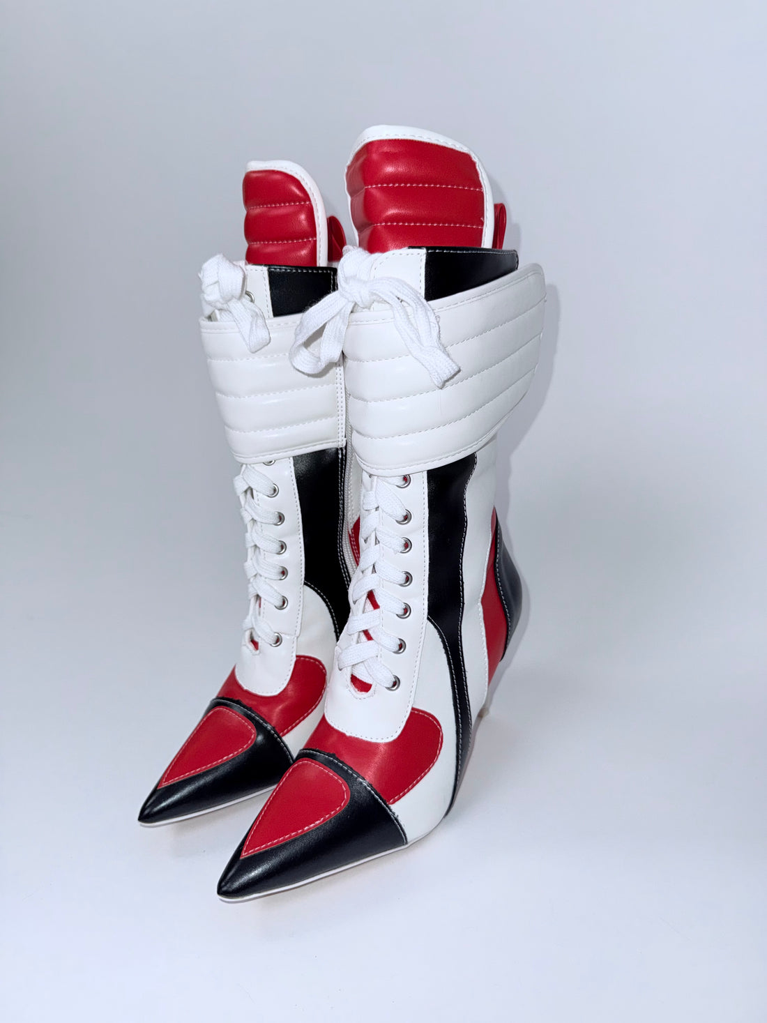 White, red, and black high-heeled boots on a light gray background