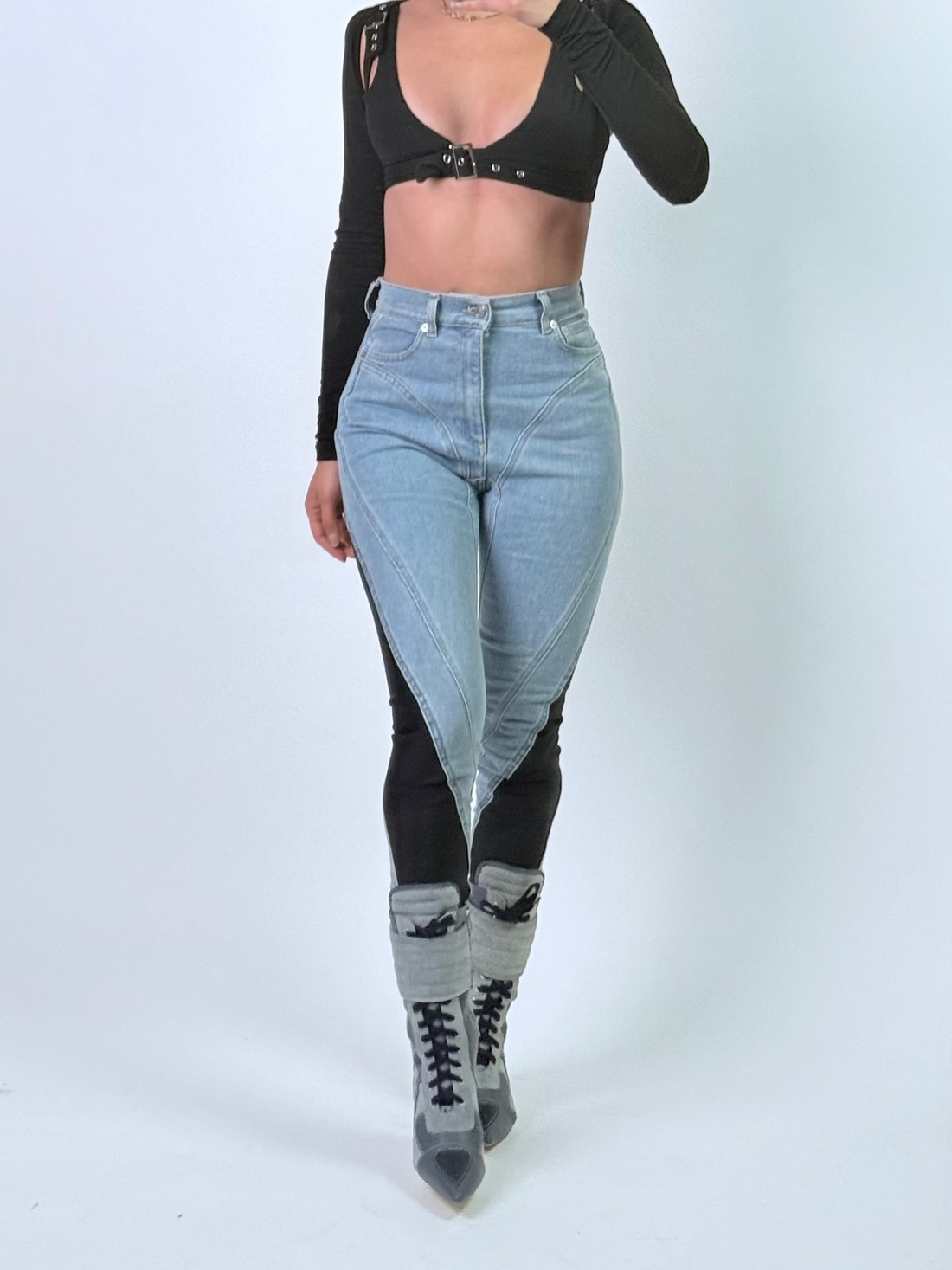 Person wearing a black crop top and light blue jeans on a white background
