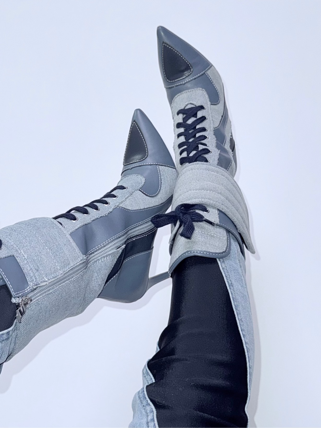 Blue denim high-heeled shoes with laces worn with light blue jeans on a white background